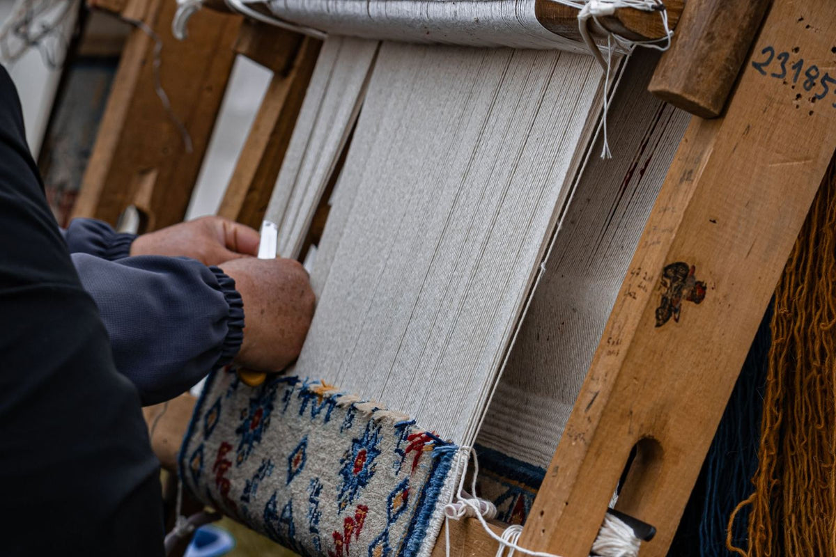 Artisan nouant un tapis à la main sur un métier à tisser